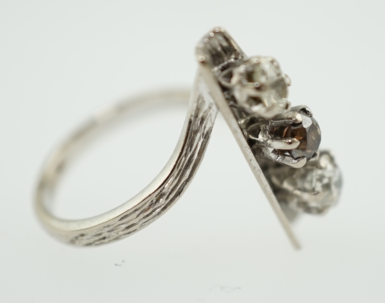 A 1970's 18ct white gold and graduated three stone diamond modernist ring